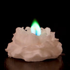 Biala sniezna swieca w ksztalcie rozy z zielono-niebieskim plomieniem na ciemnym tle