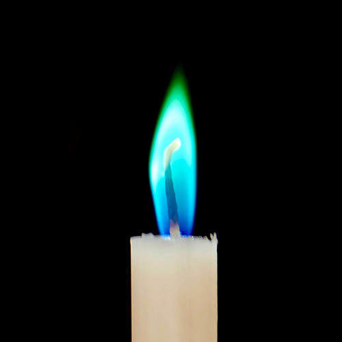 Zbliżenie świecy z kolorowym  płomieniem na czarnym tle